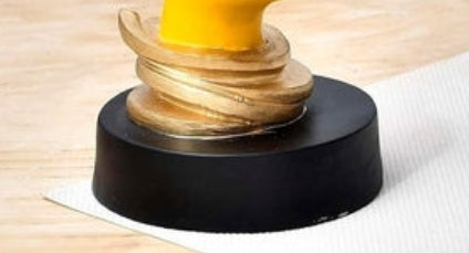 Escultura abstracta moderna de rostro amarillo sobre base dorada