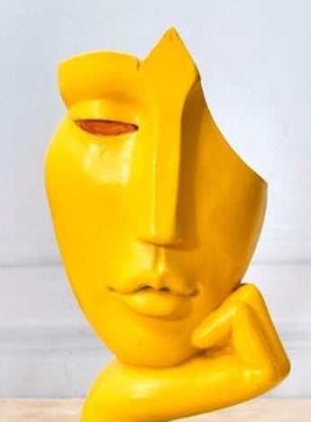 Escultura abstracta moderna de rostro amarillo sobre base dorada